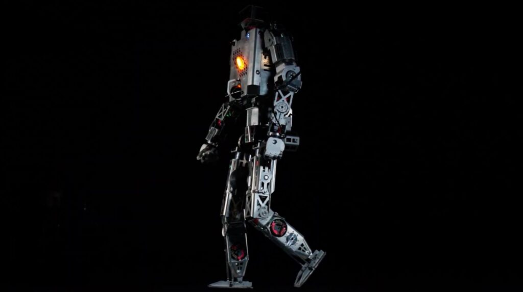 Minerva’s Roger humanoid prototype in profile against a black background, with one leg raised.